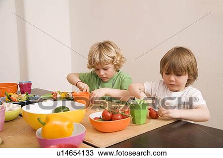 Stock Image - Two boys cutting vegetables. Fotosearch
