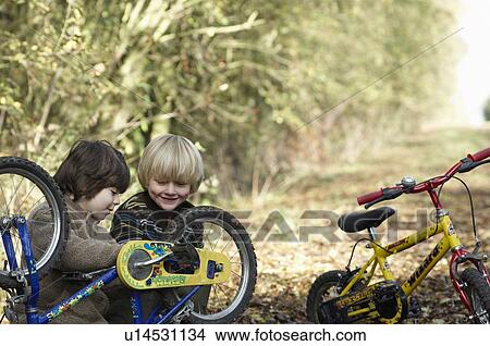 Two boys examine bikes on country lane View Large Photo Image Picture - Two boys examine bikes on country lane. Fotosearch