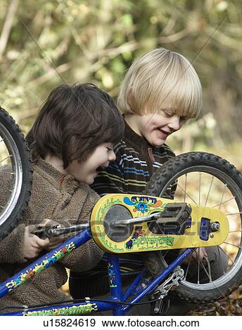 Stock Photo - Two boys examine bikes on country lane. Fotosearch
