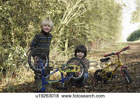 Two boys examine bikes on country lane View Large Photo Image Stock Photo - Two boys examine bikes on country lane. Fotosearch