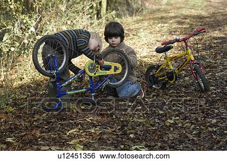 Stock Photograph - Two boys examine bikes on country lane. Fotosearch