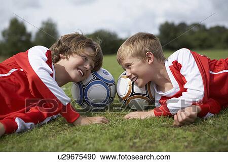 Stock Image - Two boys laughing with heads on balls. Fotosearch