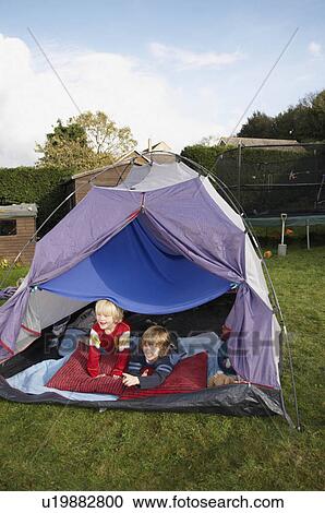 Stock Image - Two boys looking out of tent. Fotosearch