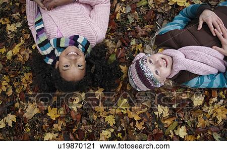 Stock Image - Two friends lying on autumn leaves. Fotosearch