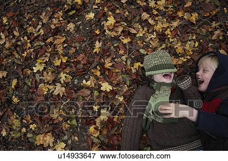 Two friends lying on autumn leaves View Large Photo Image Stock Photo - Two friends lying on autumn leaves. Fotosearch