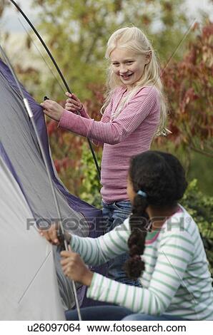 Picture - Two girls erecting tent. Fotosearch