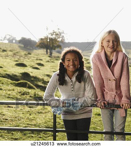 Stock Image - Two girls on gate in countryside. Fotosearch