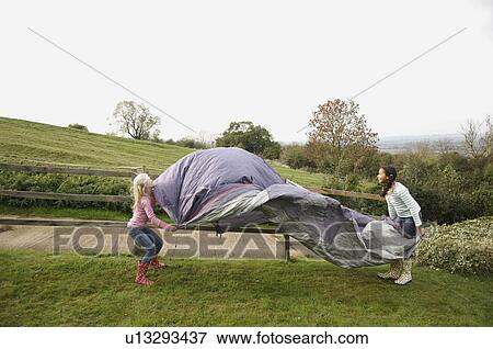 Stock Photo - Two girls putting up tent. Fotosearch