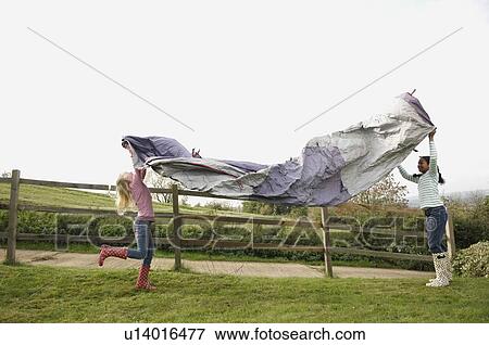 Stock Photo - Two girls putting up tent. Fotosearch