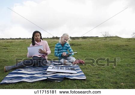 Two girls sketching on hillside View Large Photo Image Stock Image - Two girls sketching on hillside. Fotosearch