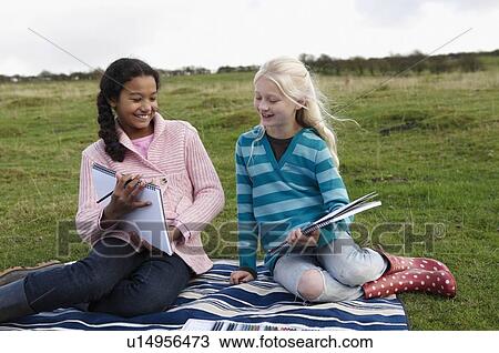 Two girls sketching on hillside View Large Photo Image Stock Image - Two girls sketching on hillside. Fotosearch