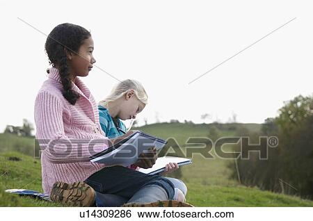 Stock Photograph - Two girls sketching on hillside. Fotosearch