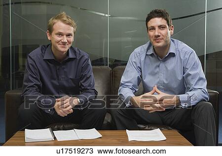Two men sitting on sofa View Large Photo Image Stock Image - Two men sitting on sofa. Fotosearch