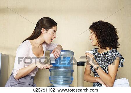 Two women are chatting by water cooler View Large Photo Image Stock Image - Two women are chatting by water cooler. Fotosearch