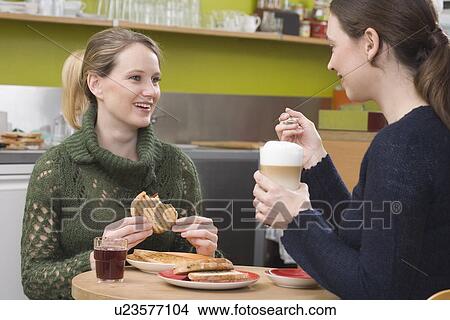 Picture - "Two women in coffee shop, talking". Fotosearch