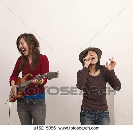 Two women singing and playing guitar View Large Photo Image Stock Photograph - Two women singing and playing guitar. Fotosearch