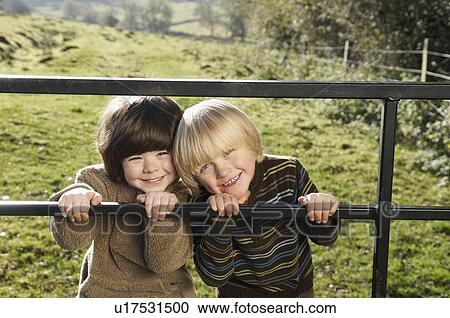 Two young boys on gate in countryside View Large Photo Image Stock Image - Two young boys on gate in countryside. Fotosearch
