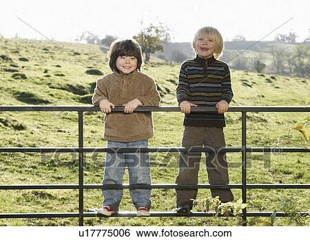 Two young boys on gate in countryside View Large Photo Image Stock Photograph - Two young boys on gate in countryside. Fotosearch