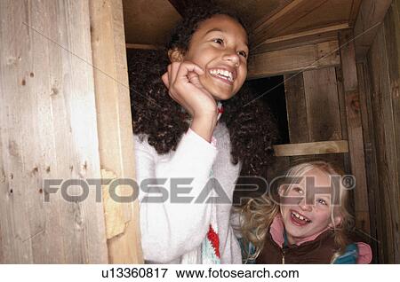 Stock Photo - Two young girls at treehouse door. Fotosearch