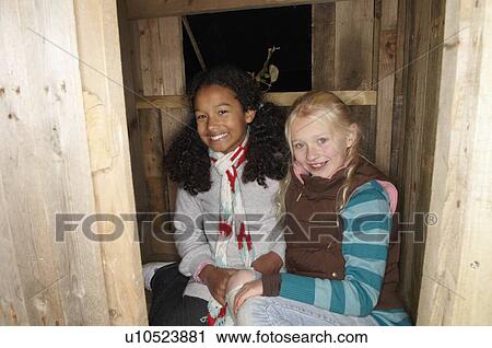 Stock Image - Two young girls in treehouse. Fotosearch
