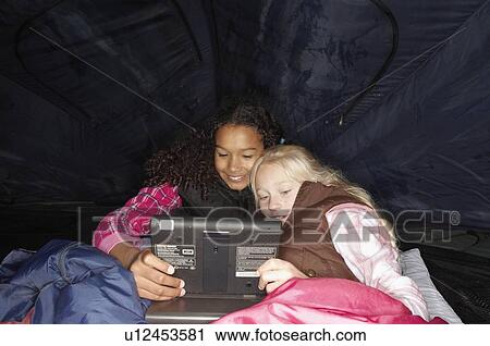 Stock Image - Watching DVD in tent. Fotosearch