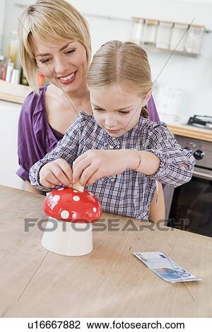 Stock Image - Woman and girl sitting at table playing. Fotosearch
