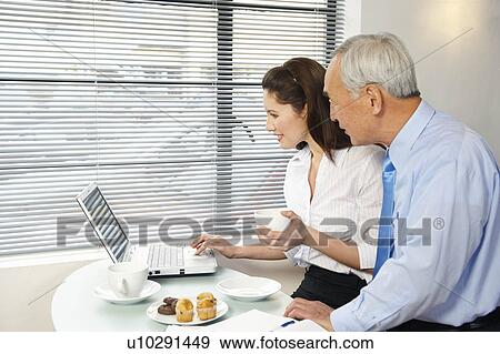 Stock Photo - Woman and senior man looking at laptop. Fotosearch