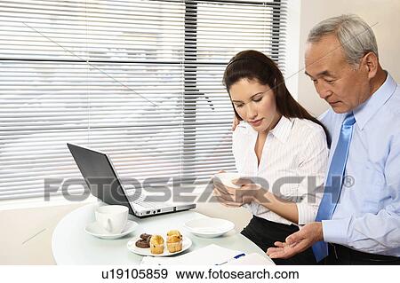 Stock Photo - Woman and senior man looking at papers. Fotosearch