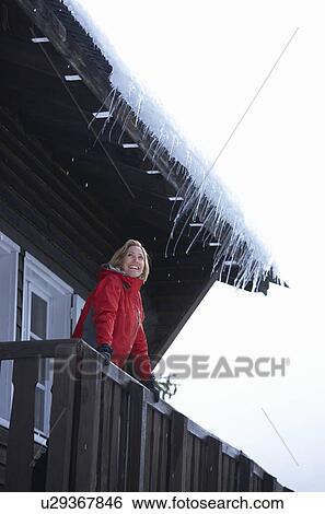 Stock Photograph - Woman at balcony of chalet. Fotosearch