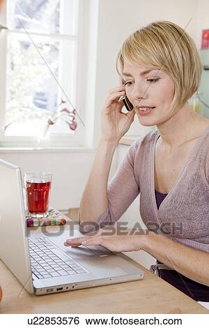 Woman at table talking on a phone View Large Photo Image Stock Photograph - Woman at table talking on a phone. Fotosearch