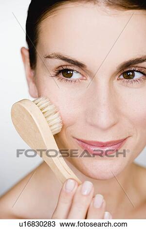 Stock Image - Woman brush massage her face. Fotosearch