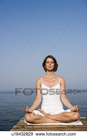 Woman doing yoga on a pier View Large Photo Image Stock Photo - Woman doing yoga on a pier. Fotosearch