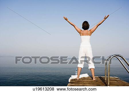 Stock Photo - Woman doing yoga on a pier. Fotosearch