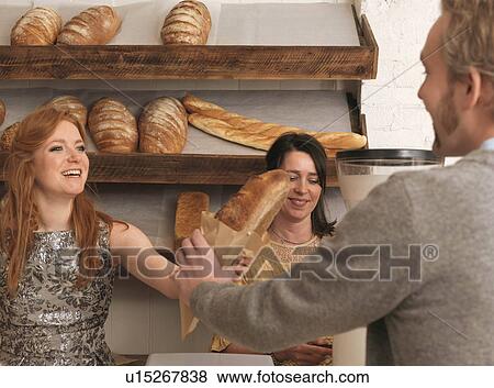 Woman handing bread to customer View Large Photo Image Stock Photo - Woman handing bread to customer. Fotosearch