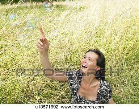 Stock Image - "Woman in a field, soap bubbles". Fotosearch