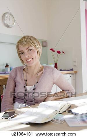Stock Image - Woman in kitchen smiling at viewer. Fotosearch