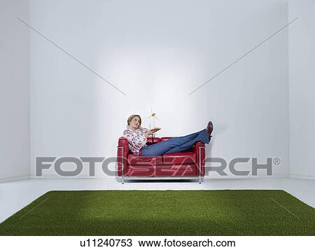 Stock Image - Woman laying on sofa with windwheel. Fotosearch