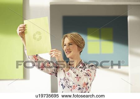 Stock Photography - Woman looking at recycling logo. Fotosearch
