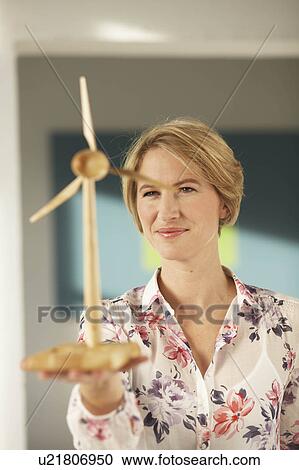 Stock Image - Woman looking at wooden wind wheel. Fotosearch