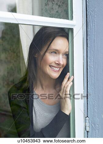 "Woman looking through window, smiling" View Large Photo Image Stock Image - "Woman looking through window, smiling". Fotosearch