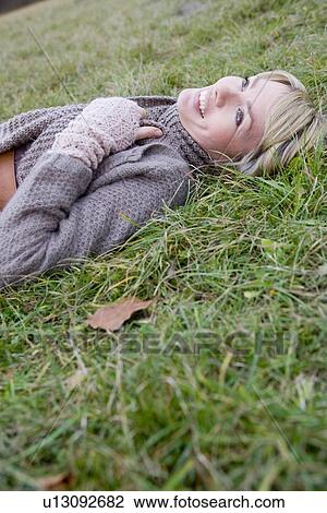 Woman lying in grass smiling View Large Photo Image Stock Image - Woman lying in grass smiling. Fotosearch