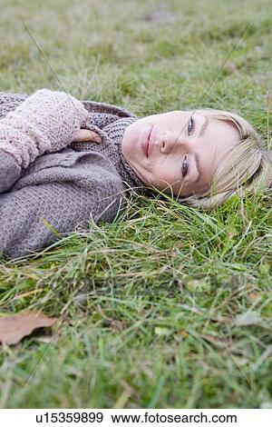 Stock Photo - Woman lying in grass smiling. Fotosearch