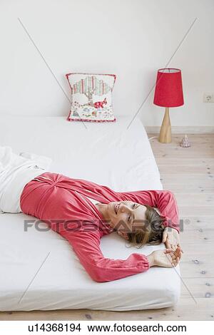 Picture - Woman lying on a bed. Fotosearch