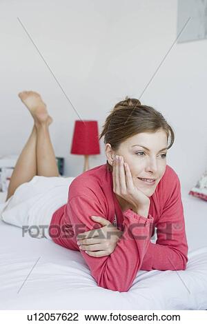 Stock Image - Woman lying on a bed. Fotosearch