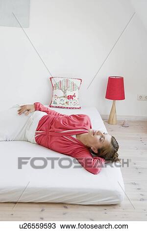 Woman lying on a bed View Large Photo Image Stock Image - Woman lying on a bed. Fotosearch