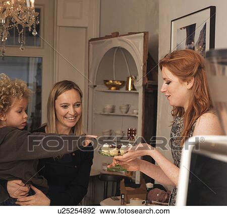 Stock Image - Woman offering cakes to young boy. Fotosearch