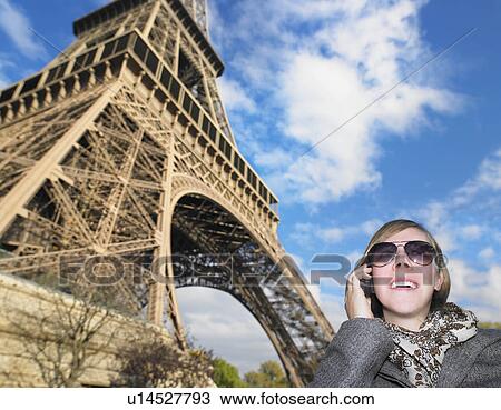 Stock Image - Woman on phone in front of Eiffel tower. Fotosearch