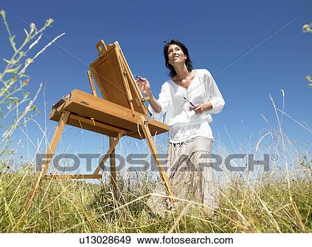 "Woman painting in a field, smiling" View Large Photo Image Stock Photo - "Woman painting in a field, smiling". Fotosearch