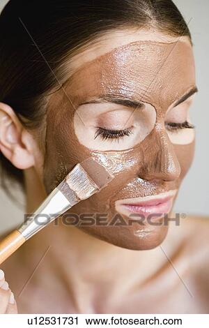 Stock Image - Woman putting face mask on. Fotosearch