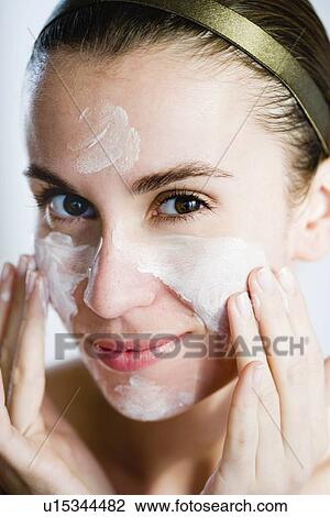 Stock Image - Woman putting face mask on. Fotosearch